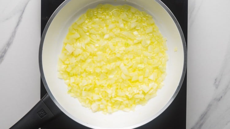 sauteing onion in a white pan