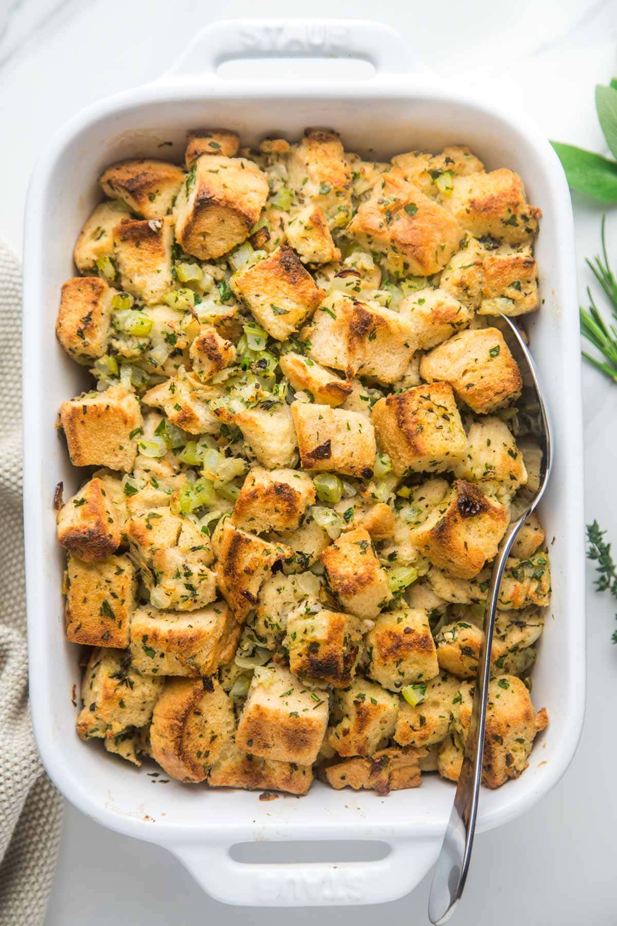 Classic stuffing in a white Staub ceramic dish, with a serving spoon - overhead shot