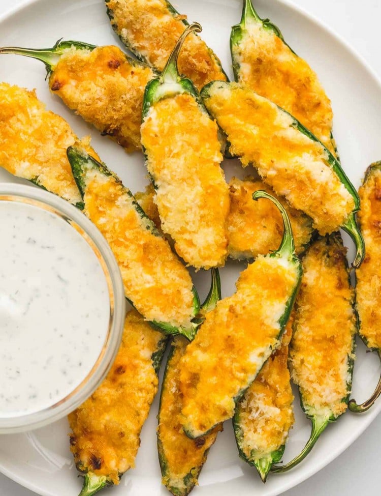 Jalapeno poppers served on a white plate with a dip