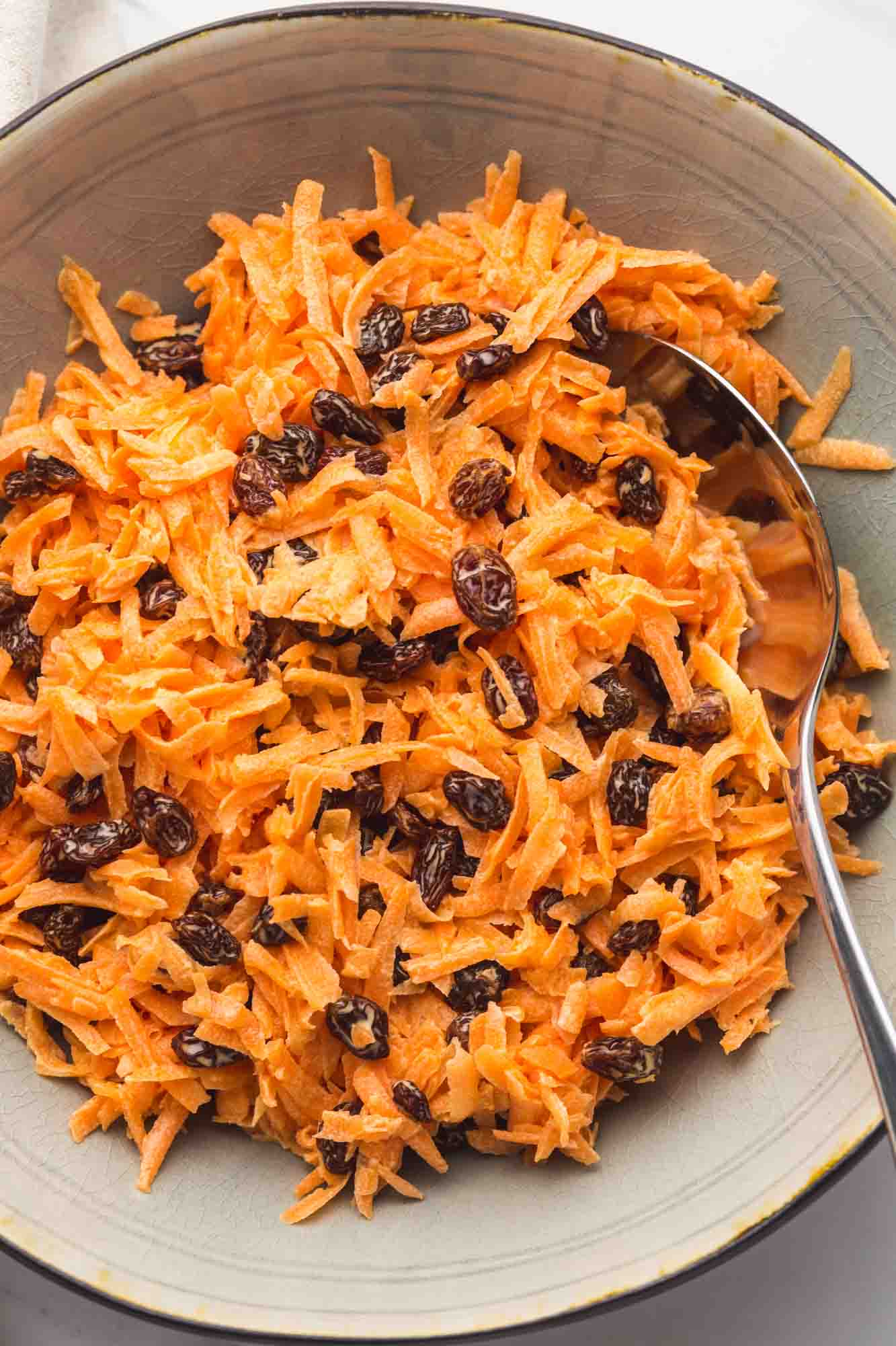 Carrot Raisin salad served in a large bowl, and a serving spoon