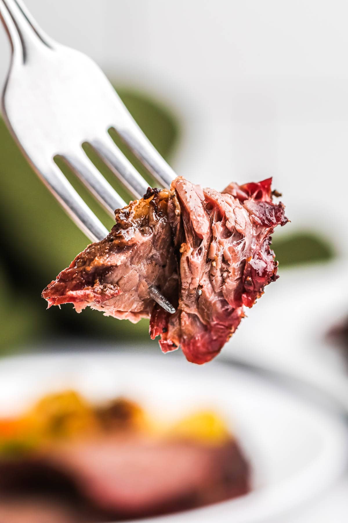 A spice of smoked beef on a fork to show tenderness of the meat
