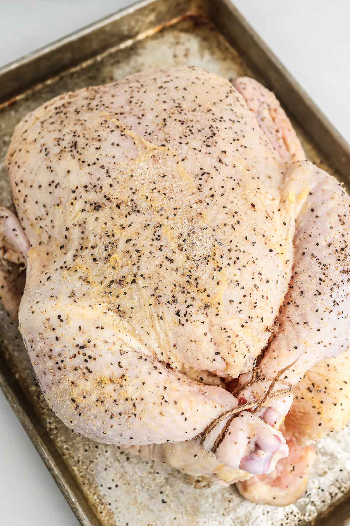 Raw and seasoned whole chicken placed on a tray