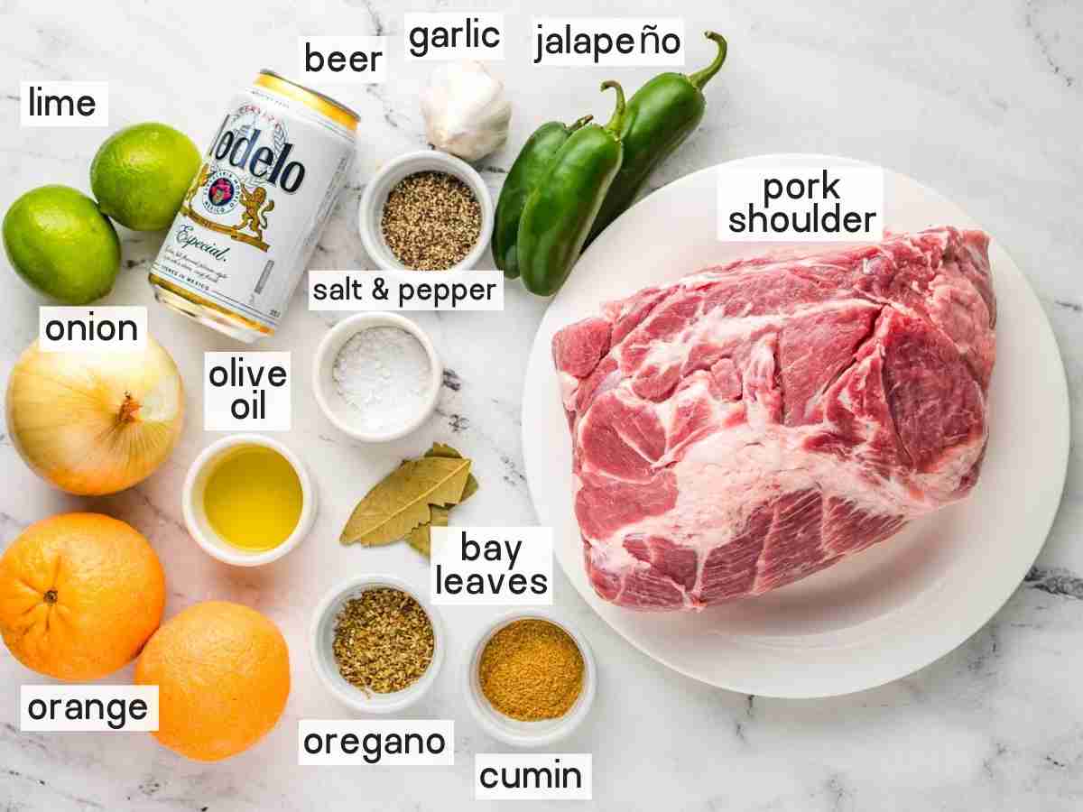 Ingredients needed to make carnitas in the instant pot including pork shoulder, modelo beer, jalapenos, oranges, limes, olive oil, garlic, bay leaves, oregano, cumin, salt, and pepper.