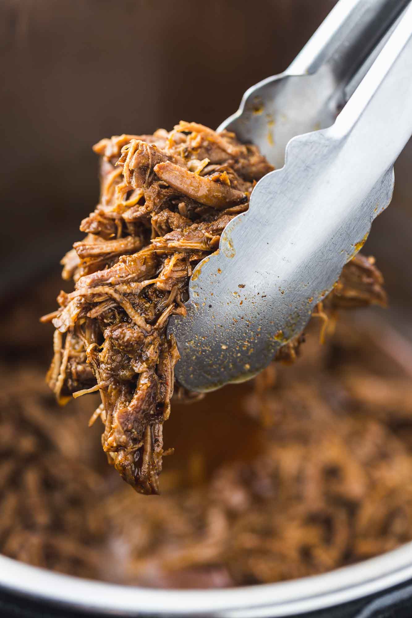 Taking a portion of shredded beef using kitchen tongs