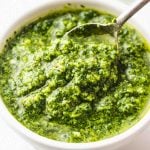 A white bowl with pesto and spoon