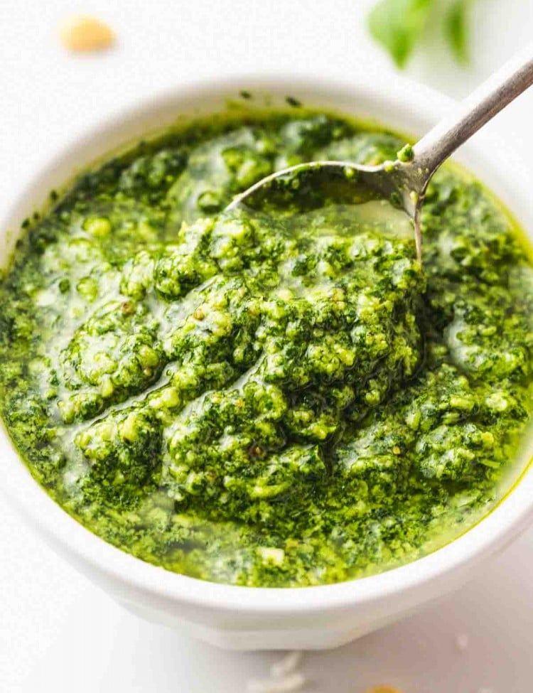 A white bowl with pesto and spoon