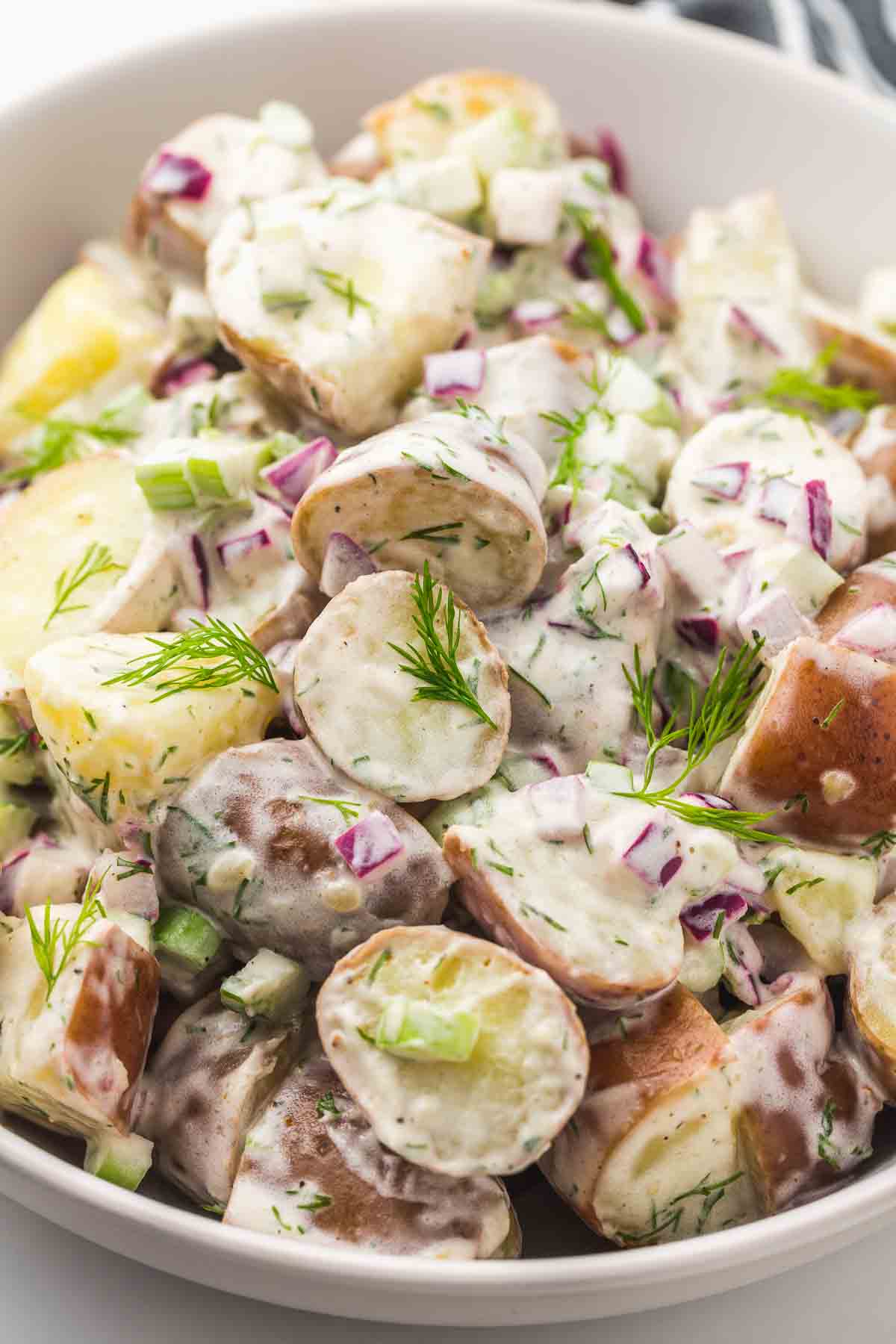 Close up shot of red potato salad in a white bowl