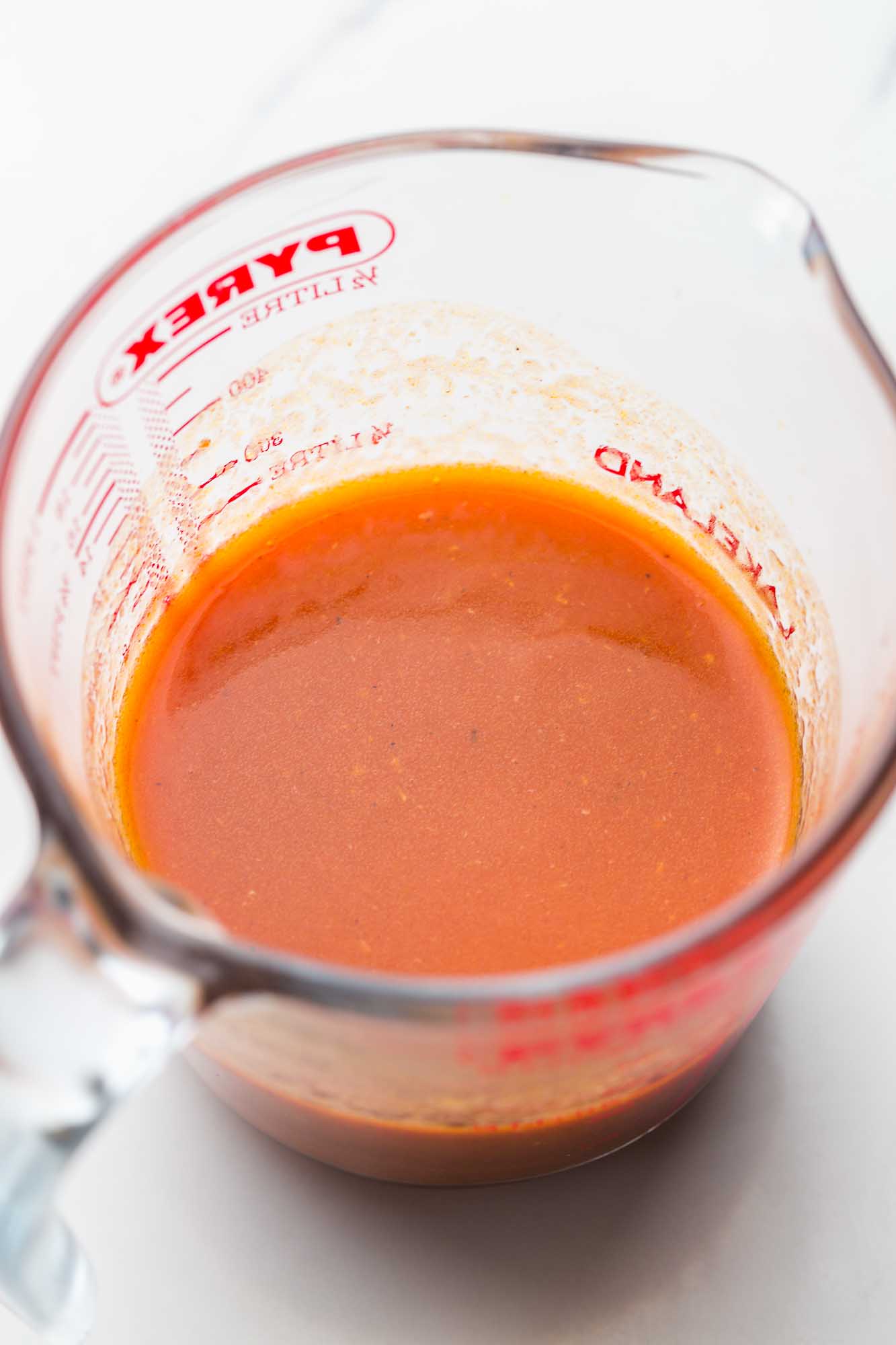 Buffalo wing sauce in a Pyrex jug