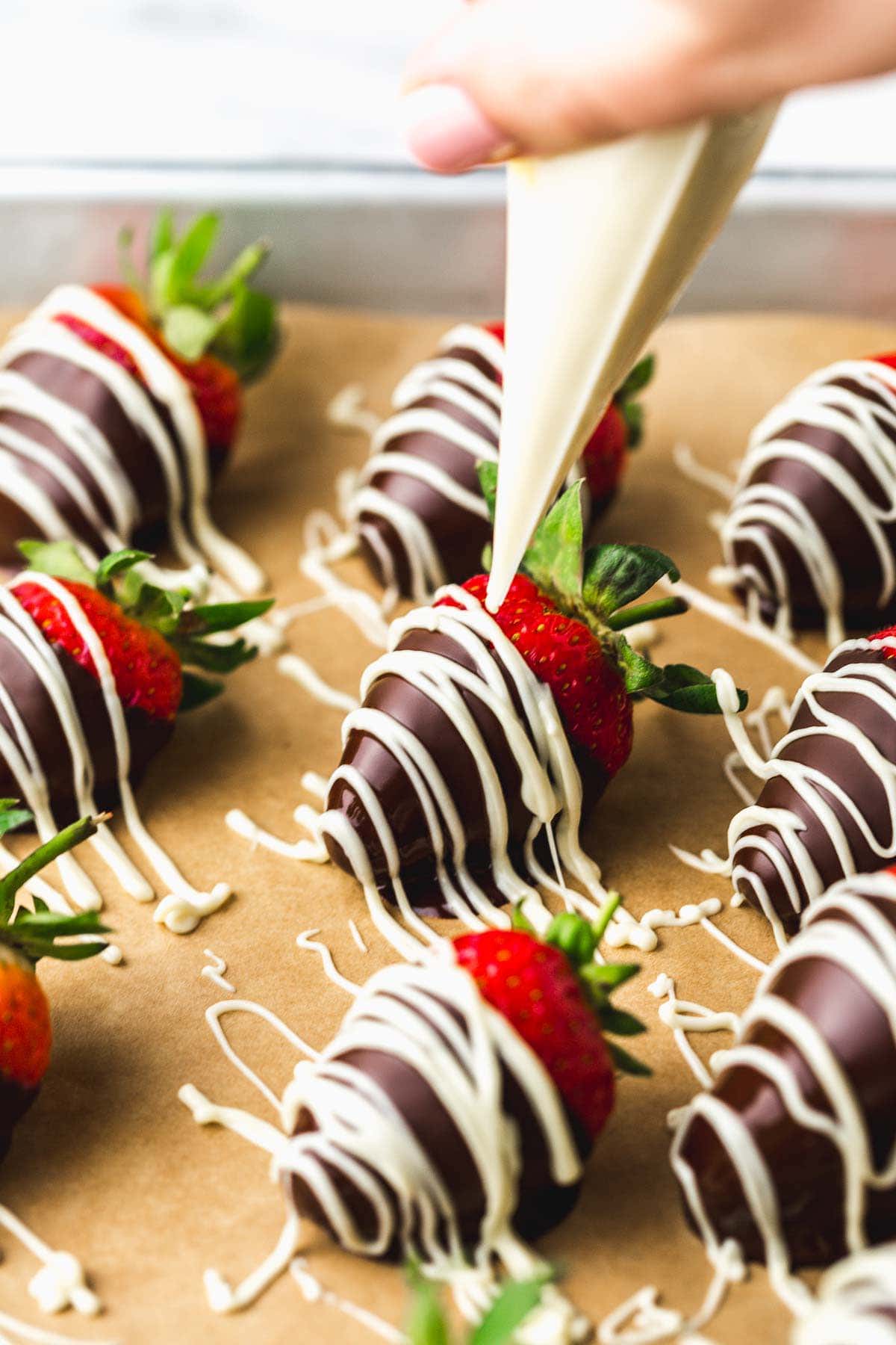 Decorating chocolate strawberries with white chocolate drizzle