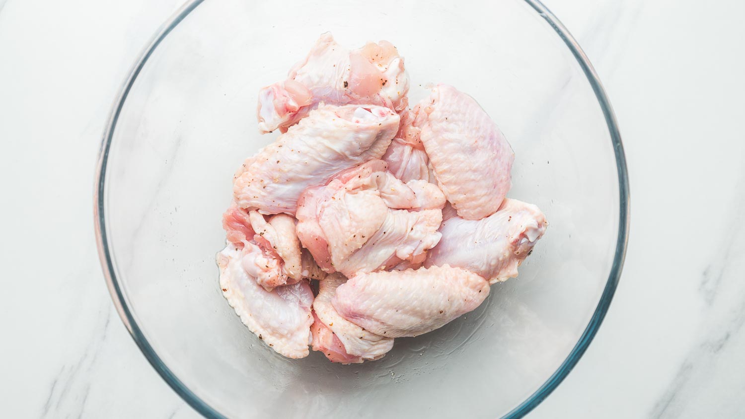 Raw chicken wings in a glass bowl