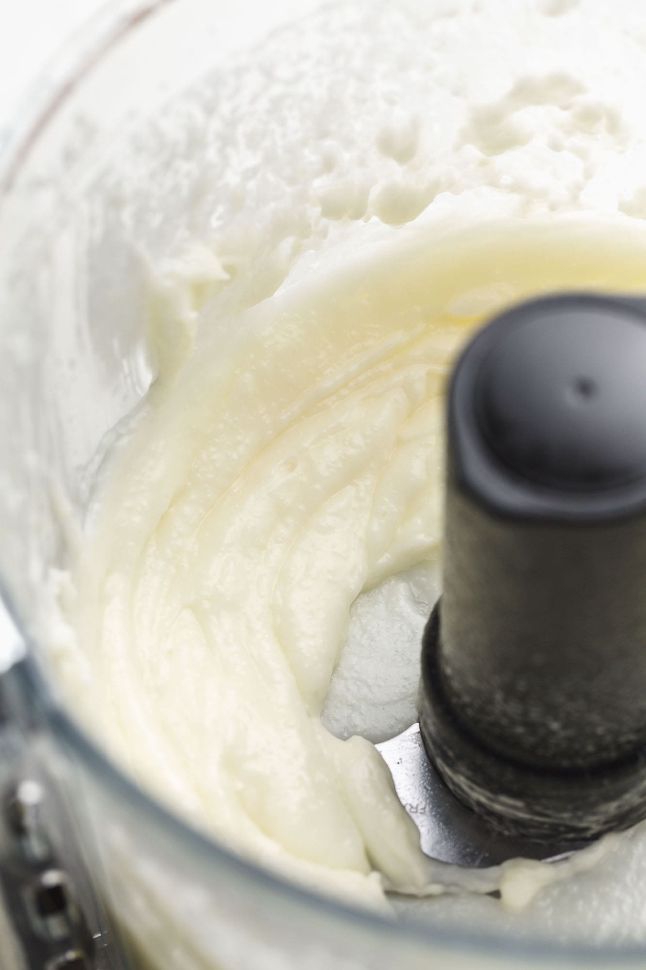 A close up shot of garlic sauce in a food processor bowl