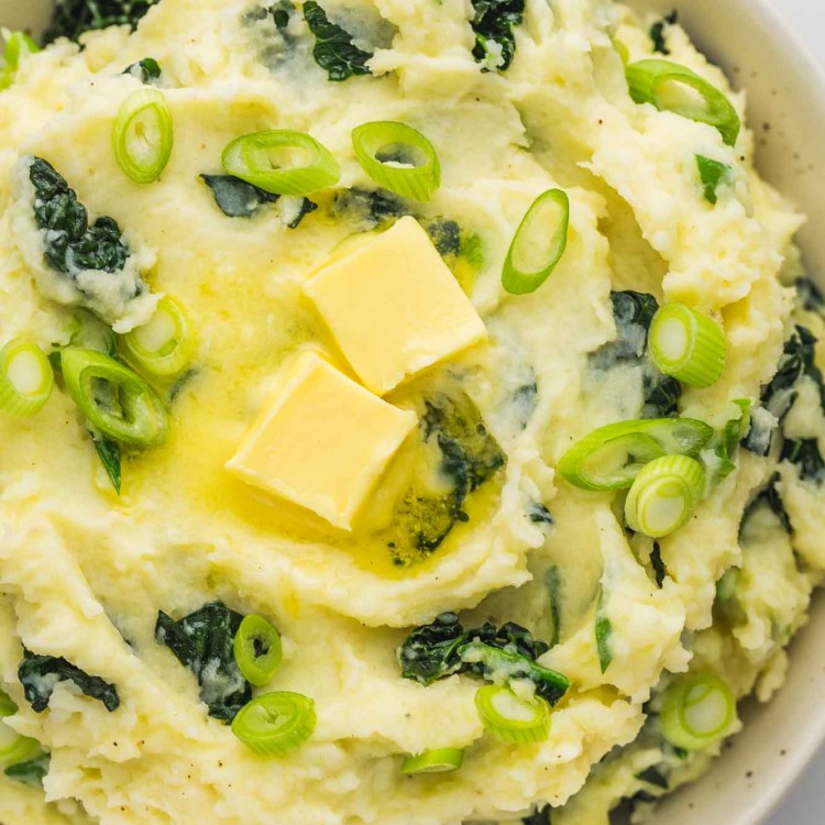 A white serving bowl with Colcannon and extra butter