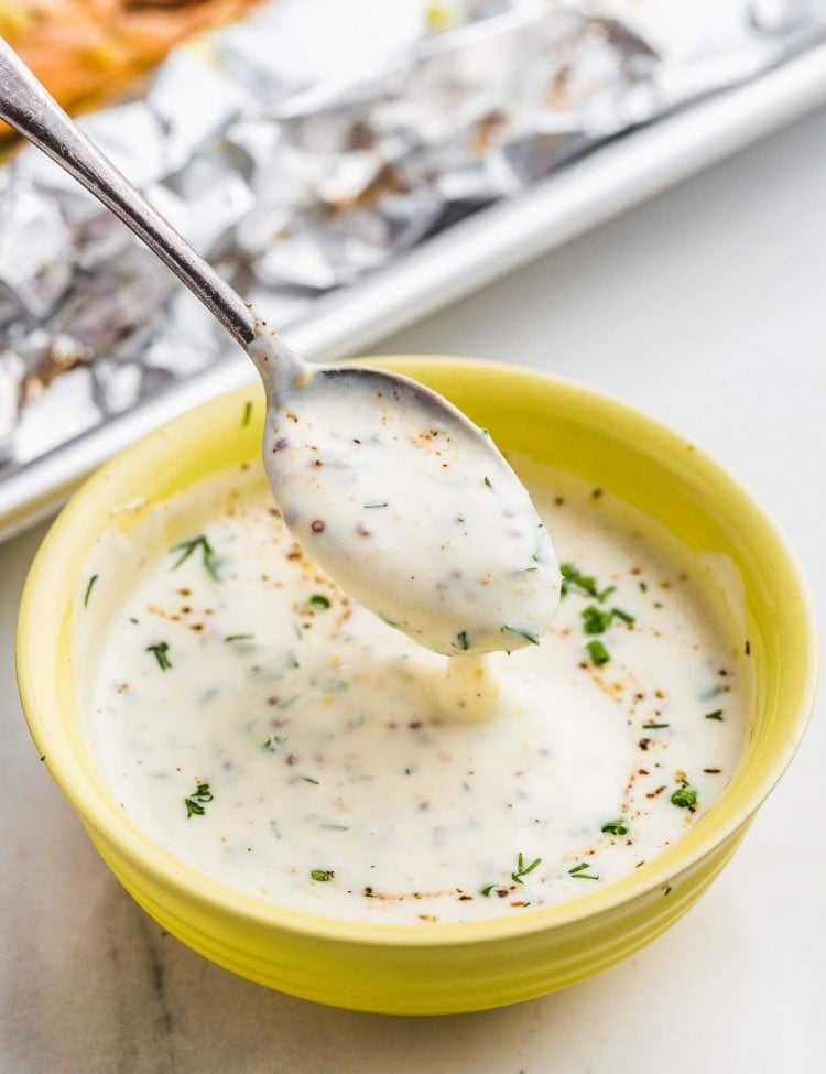 Herb cream sauce in a yellow bowl and a spoon