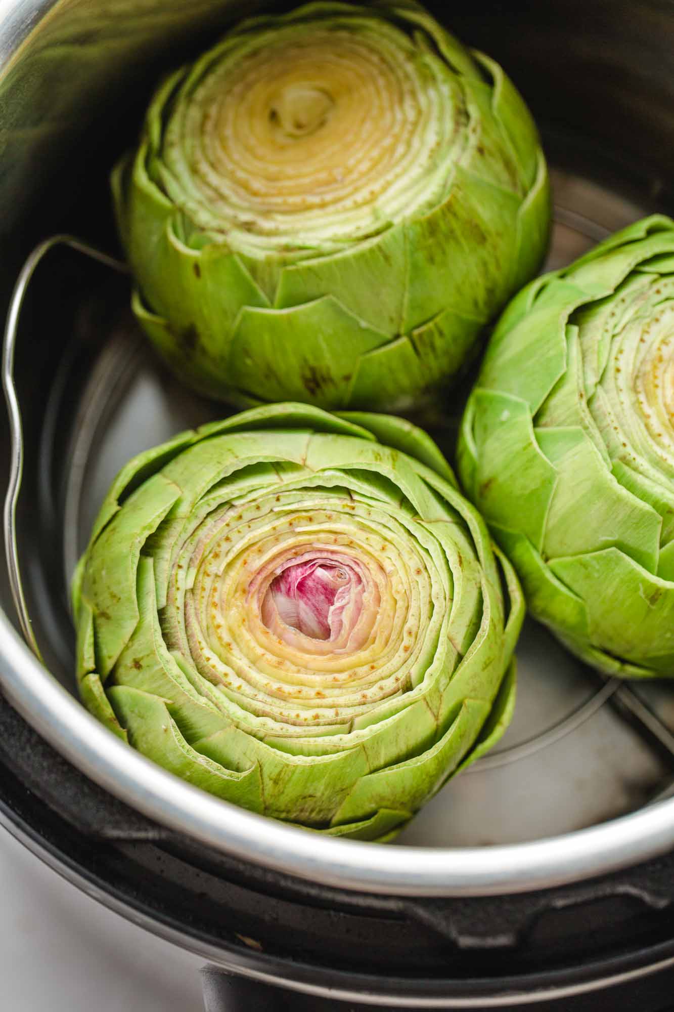 3 fresh prepped artichokes in the Instant Pot before pressure cooking.