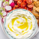A blue bowl with labneh strained yogurt and crudites in a platter