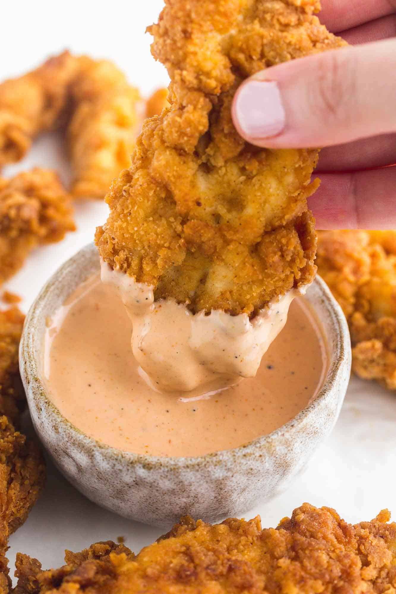 Dipping a chicken tender in Cane's Sauce