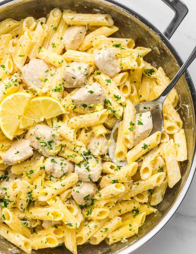Creamy Lemon Chicken Pasta in a le creuset stainless steel pan, and a serving spoon.