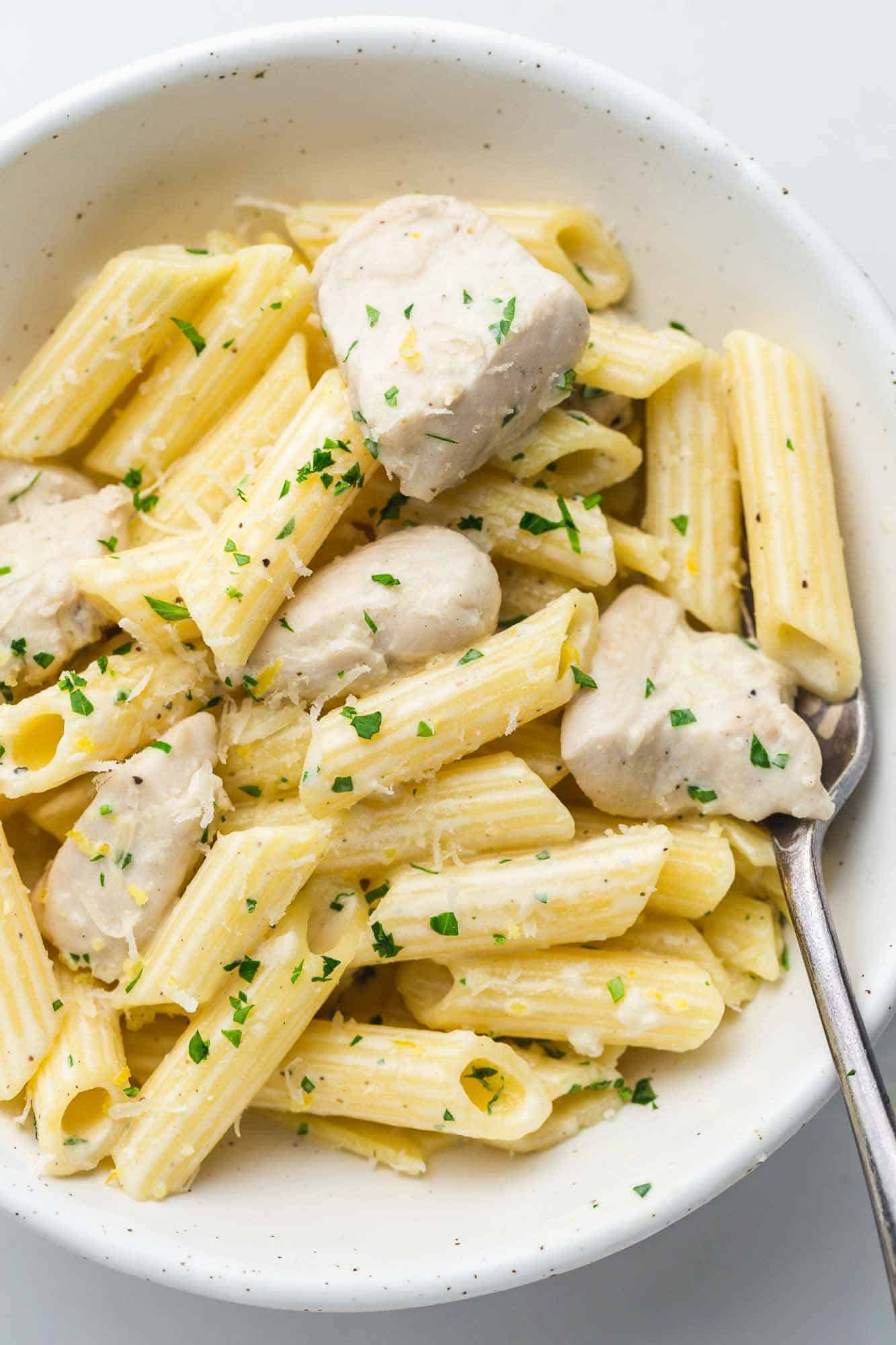 Creamy pasta and chicken served in a white bowl with a fork