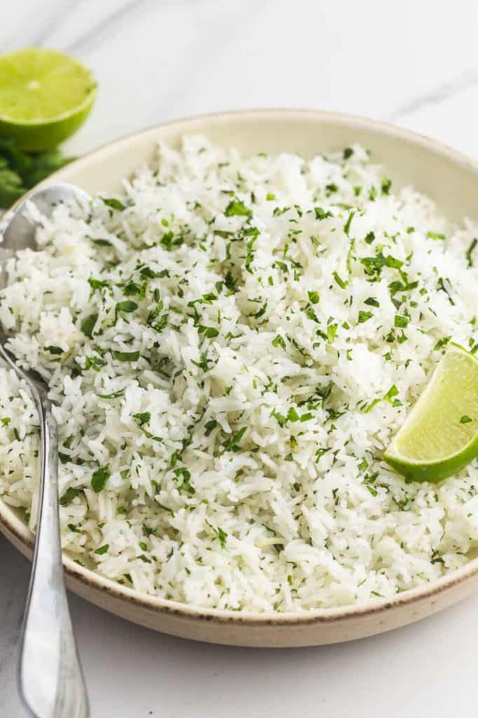 Cilantro lime rice served in a plate with fresh lime wedges