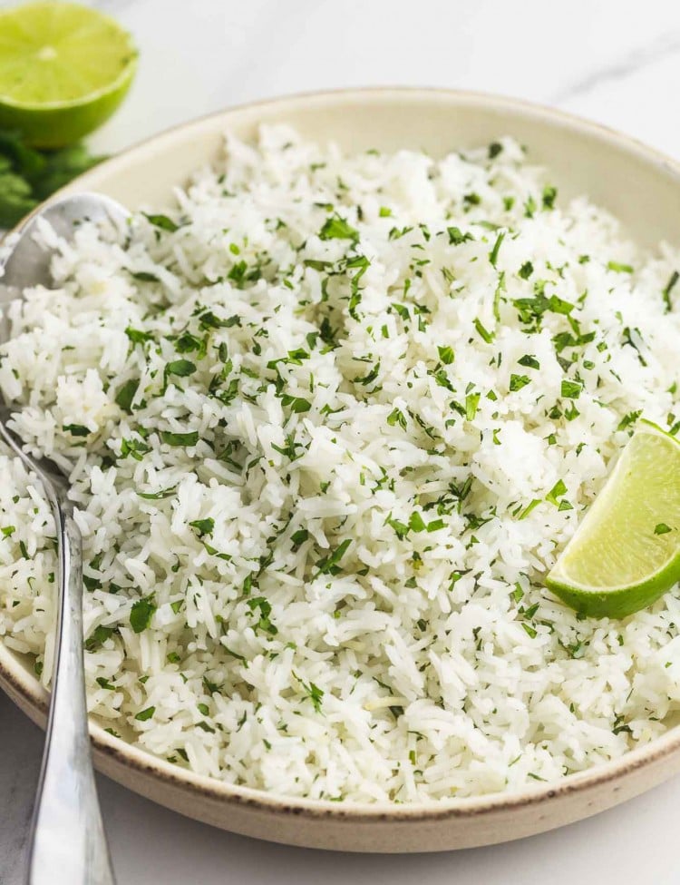 Cilantro lime rice served in a plate with fresh lime wedges