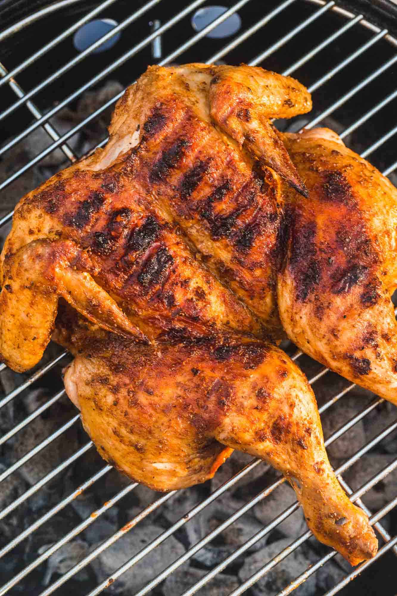 Spatchcocked grilled chicken placed on a coal grill