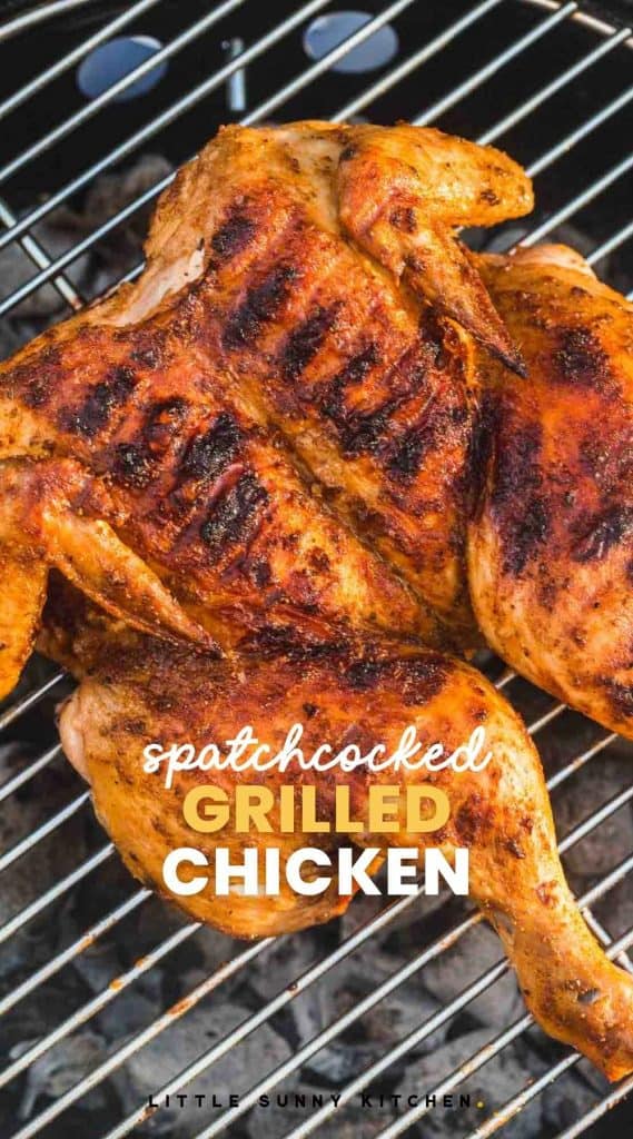 spatchcocked grilled chicken placed on a coal grill with text overlay that reads "spatchcocked grilled chicken"