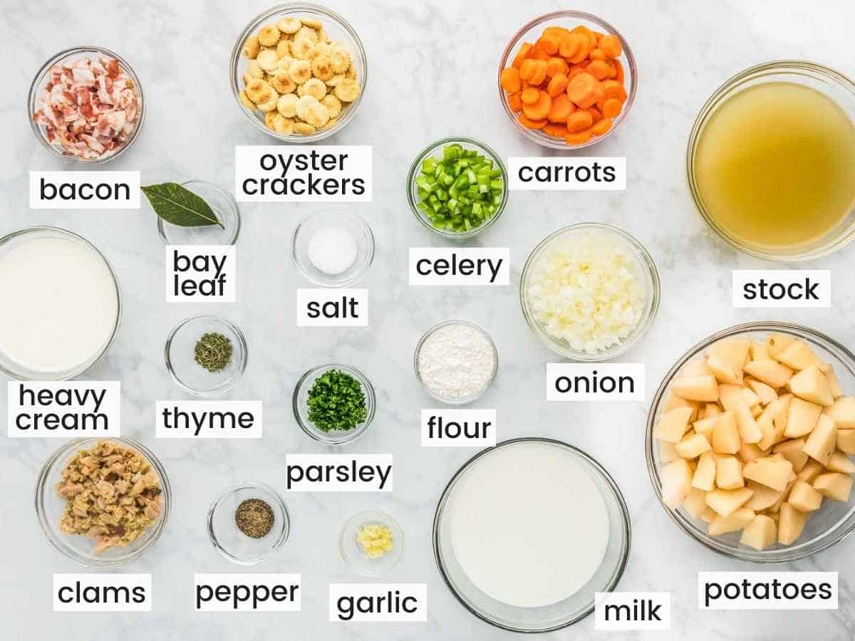 Overhead shot of ingredients needed to make clam chowder including clams, potatoes, carrots, celery, milk, cream, salt, pepper, parsley, thyme, garlic, onion, bay leaf, and bacon.