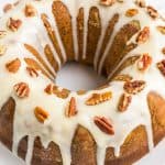 Pumpkin Bundt Cake frosted with cream cheese frosting and topped with sliced pecans