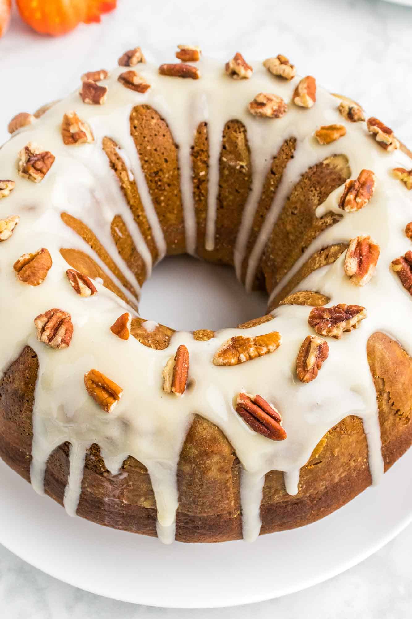 Pumpkin Bundt Cake frosted with cream cheese frosting and topped with sliced pecans