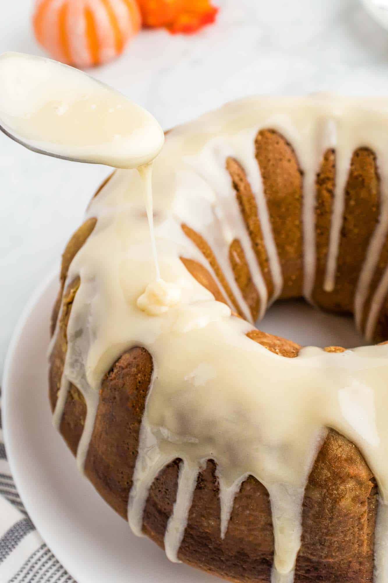 Drizzling the pumpkin bundt cake with cream cheese frosting/drizzle