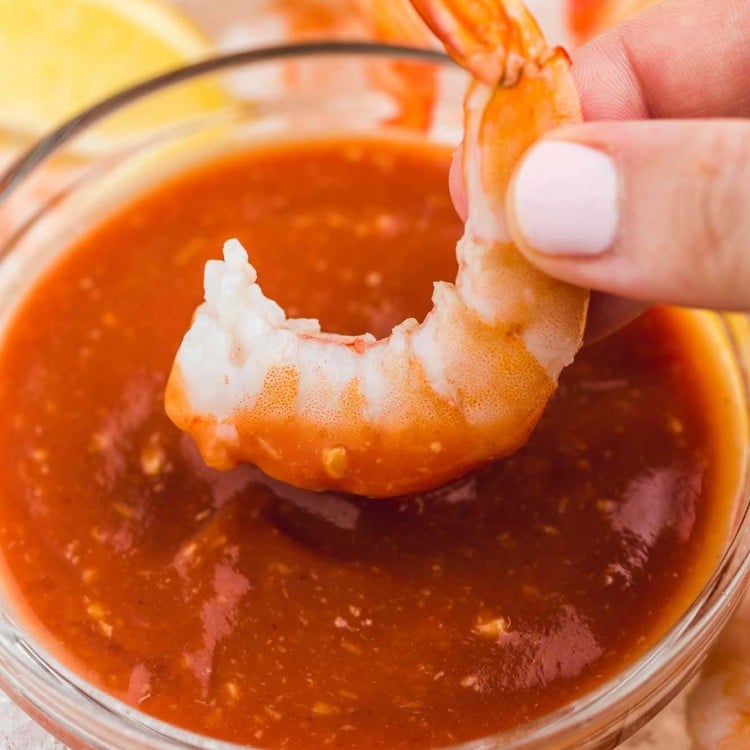 Dipping a jumbo cooked shrimp in cocktail sauce