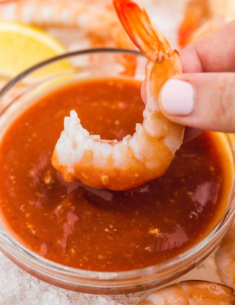 Dipping a jumbo cooked shrimp in cocktail sauce