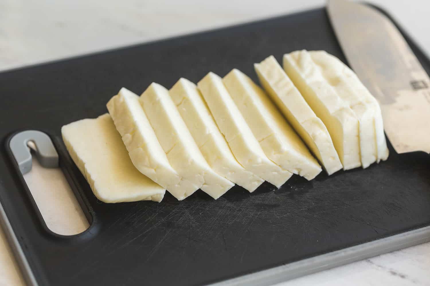 Sliced Halloumi block on a cutting board with a knife