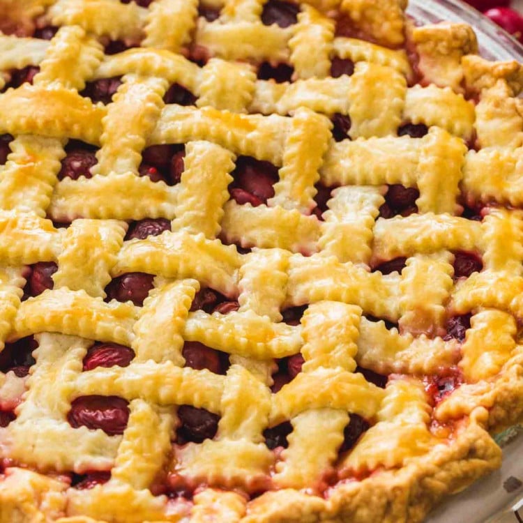 Cherry pie with lattice top, and fresh cherries on the sides