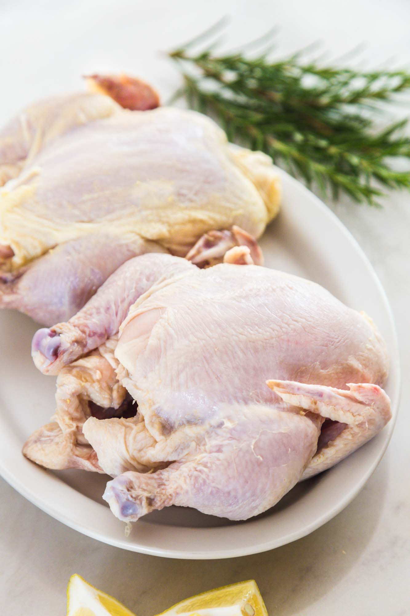 Two raw Cornish Hens placed on a white plate