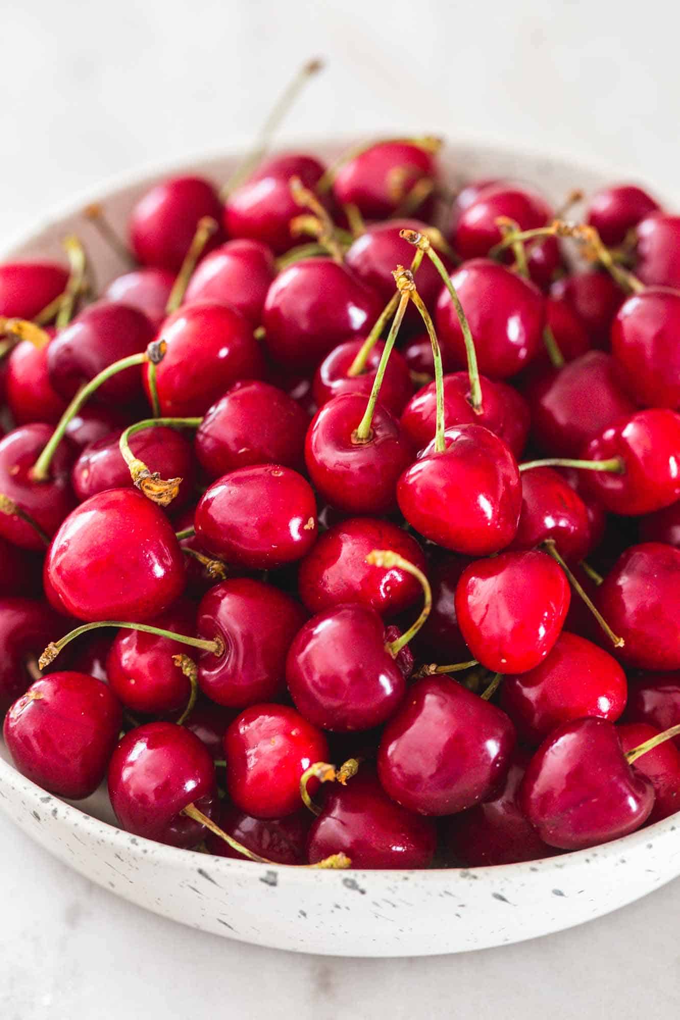 Fresh cherries in a white speckled bowl