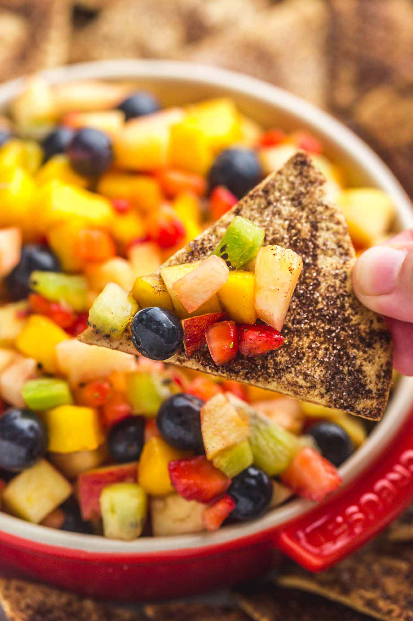 Fruit salsa served in a red Le Creuset dish, with crunchy cinnamon chips on the sides