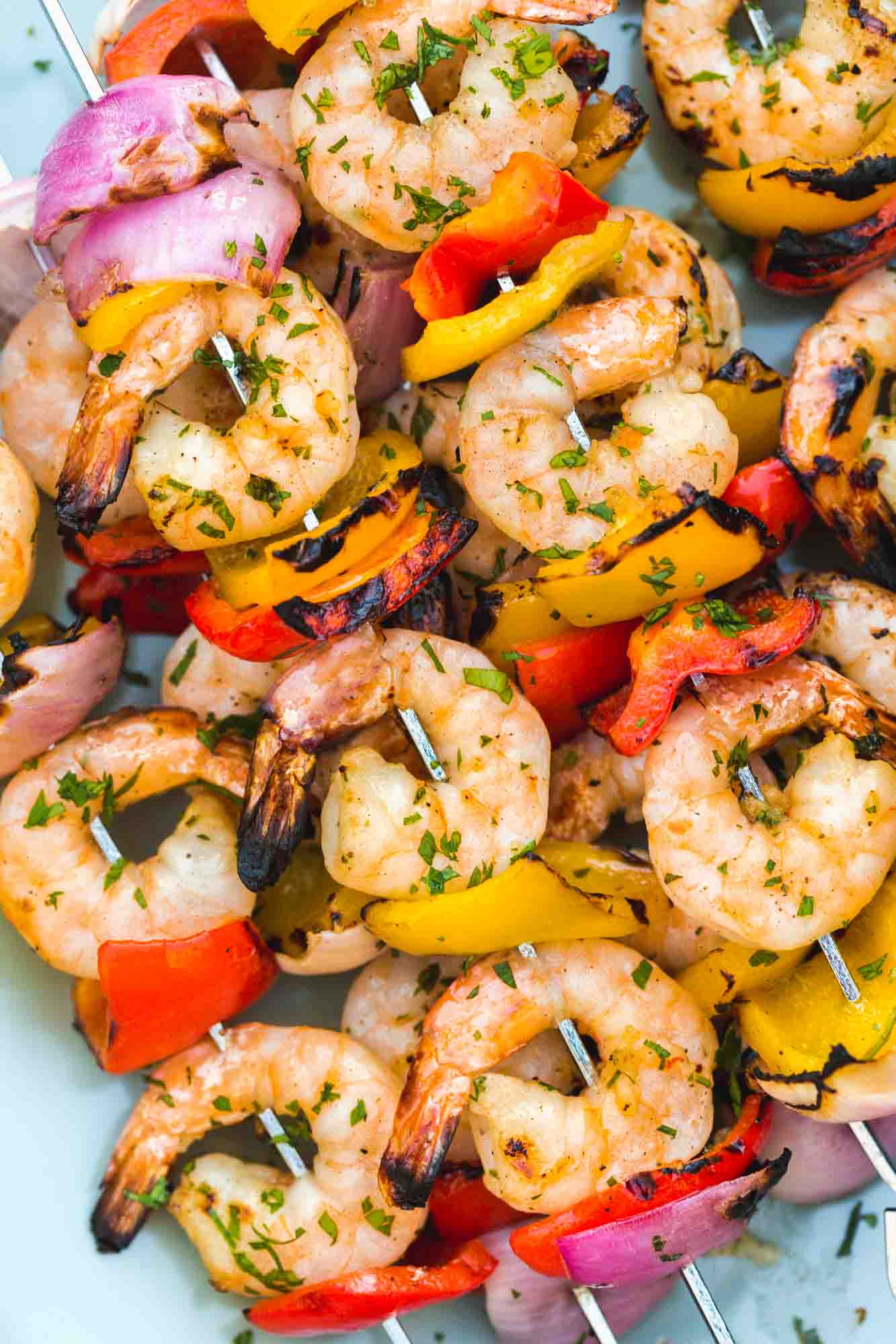 Grilled shrimp kabobs served on a blue platter, close up shot.