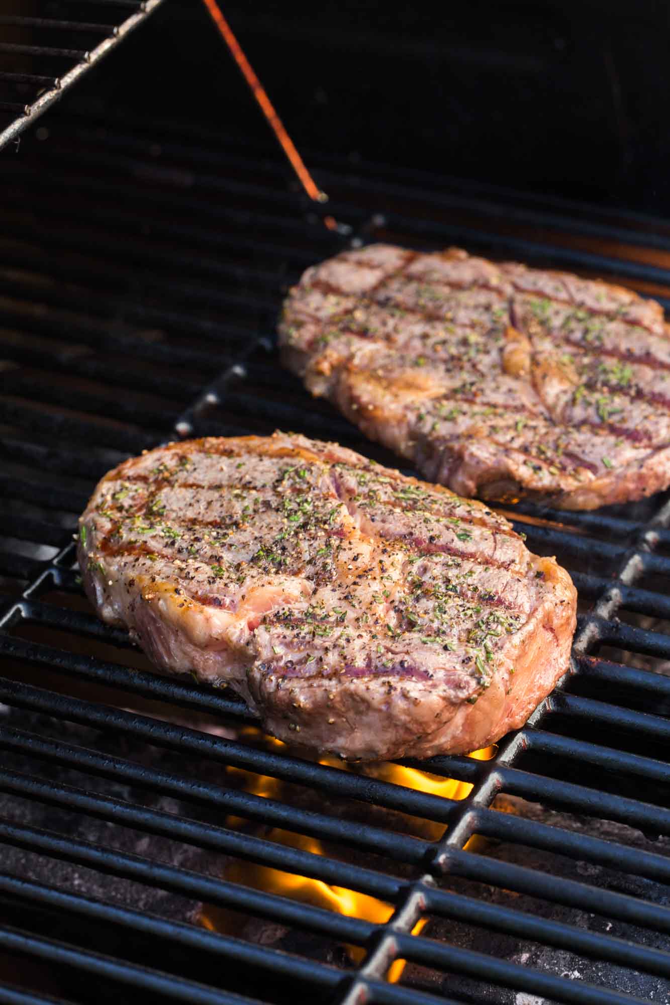 2 steaks being grilled on an outdoor gas grill