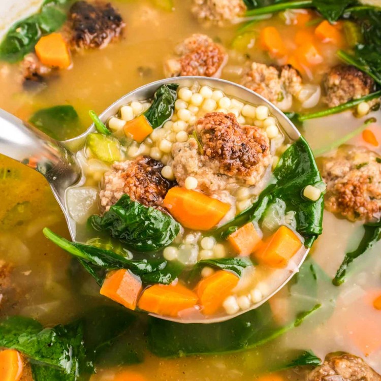 Italian wedding soup in a dutch oven and a ladle of soup
