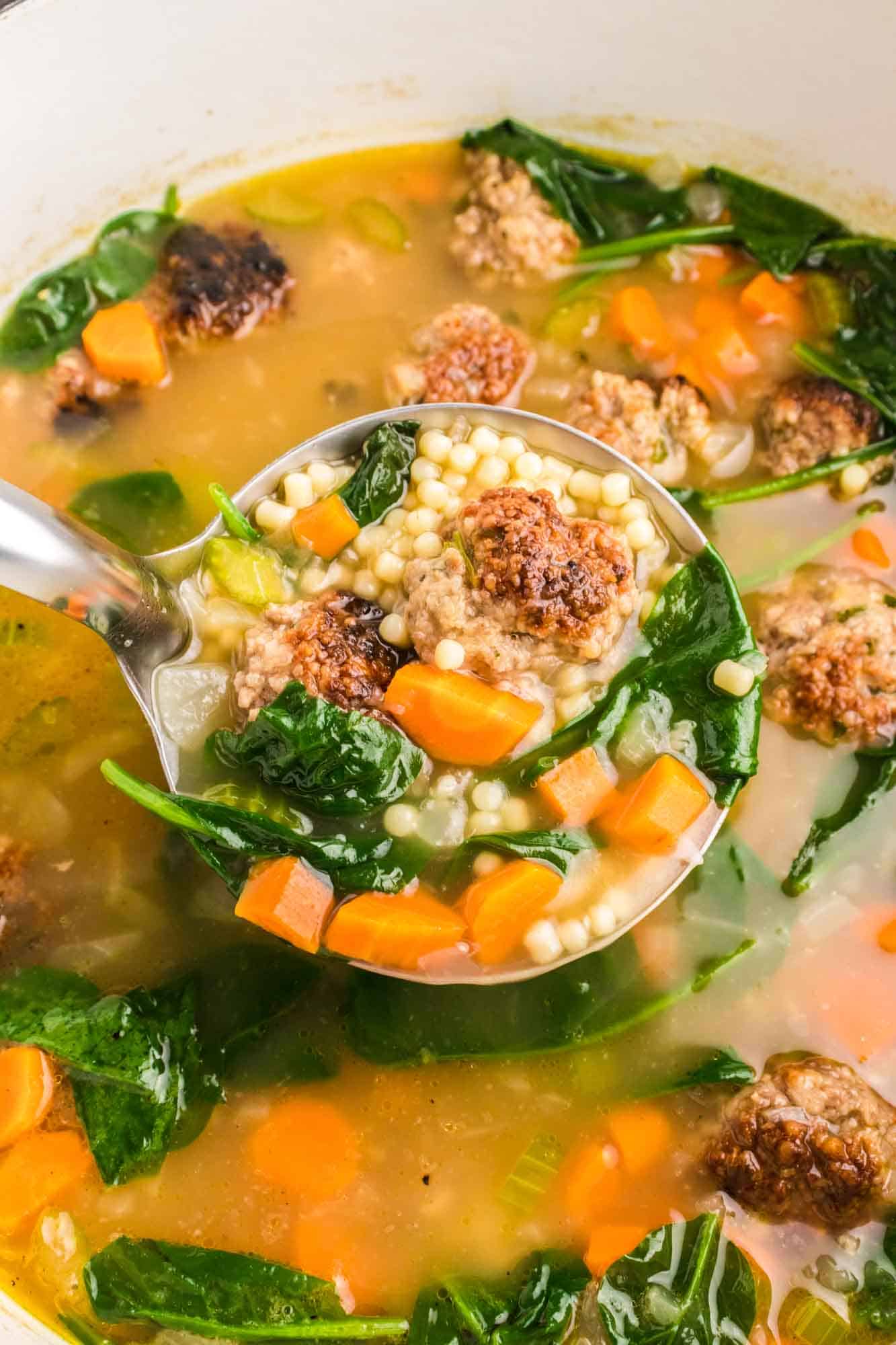 Italian wedding soup in a dutch oven and a ladle of soup