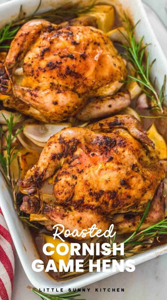 Two roasted Cornish hens in a roasting pan with rosemary and lemon, and overlay text "Roasted Cornish Game Hens"