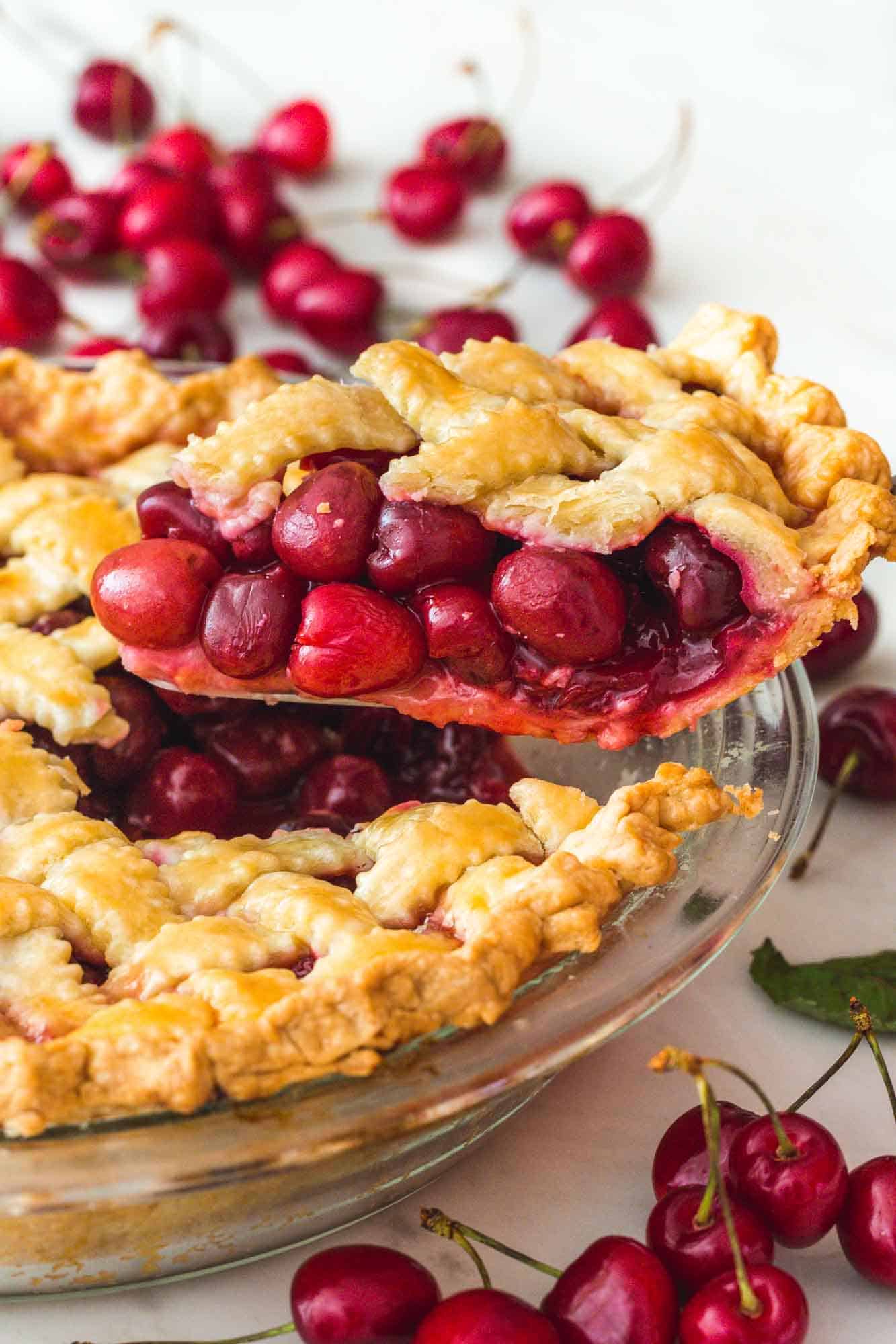 Taking a slice of the cherry pie, with fresh cherries on the sides