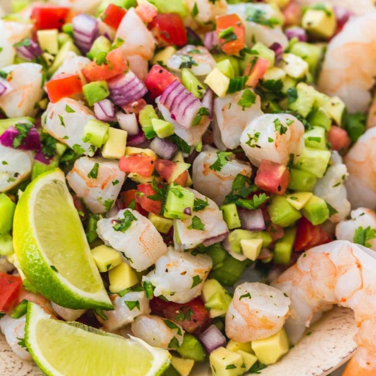 Shrimp ceviche served in a bowl with fresh lime wedges and poached shrimp