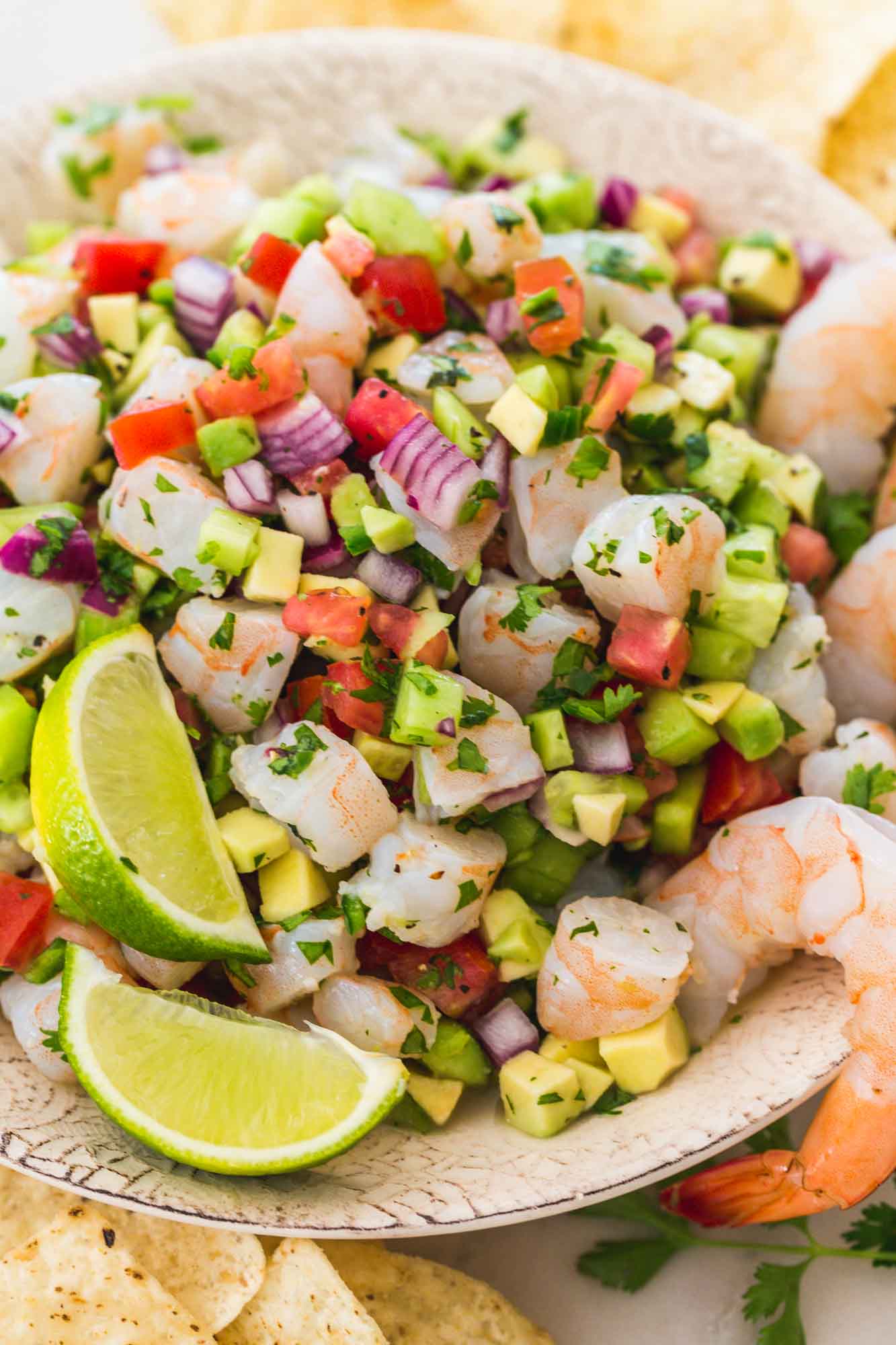 Shrimp ceviche served in a bowl with fresh lime wedges and poached shrimp