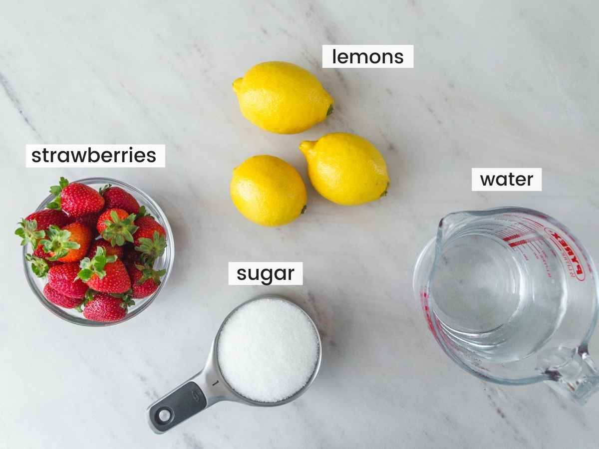 Ingredients needed for strawberry lemonade including fresh strawberries, lemons, sugar and water.
