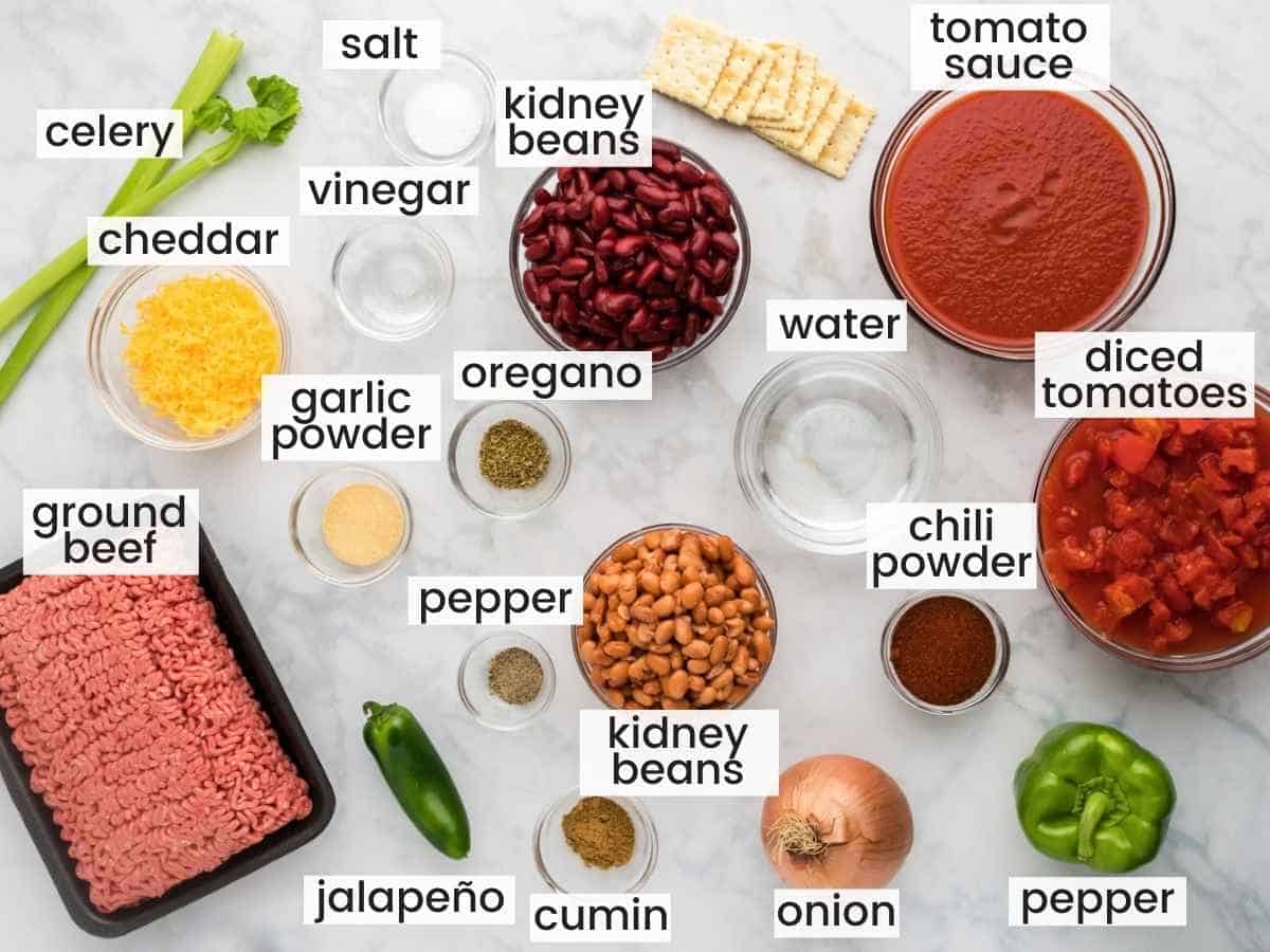 Ingredients needed to make Wendy’s Chili including ground beef, diced tomato and sauce, celery, onion, jalapeño, garlic powder, salt, pepper, cumin, pinto beans, kidney beans, cheddar, vinegar, water, bell pepper.