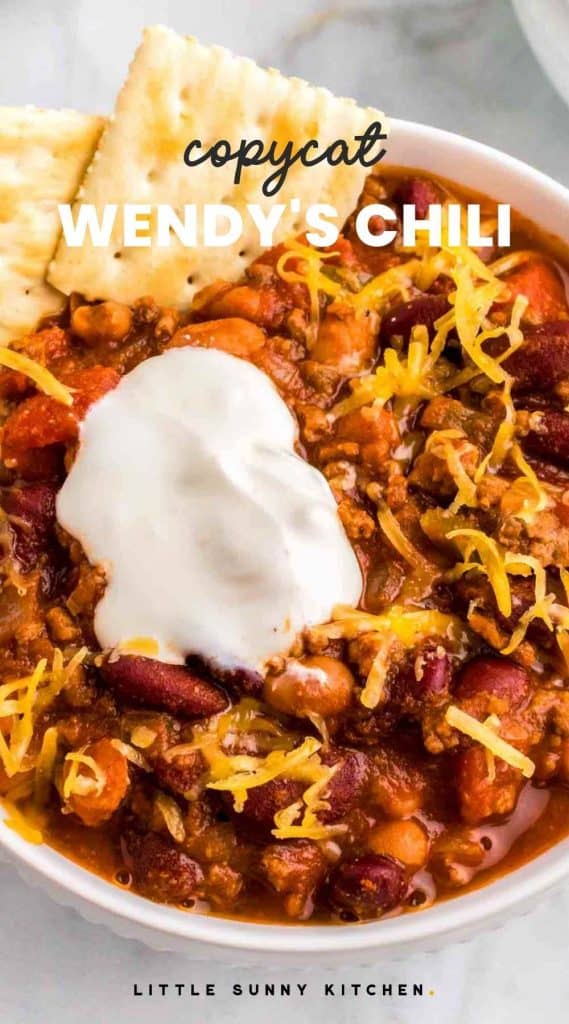 Wendy's Chili served in a white bowl with sour cream, cheese, and saltines with overlay text "Copycat Wendy's Chili"