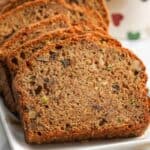 Slices of moist zucchini bread with walnuts on a white plate.