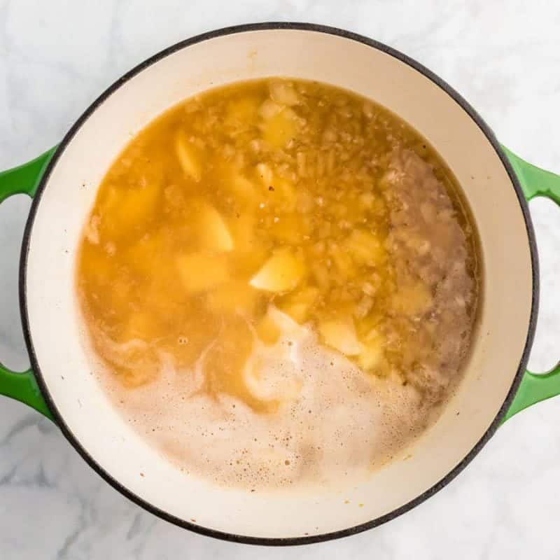 Potatoes simmering in chicken broth in a Dutch oven